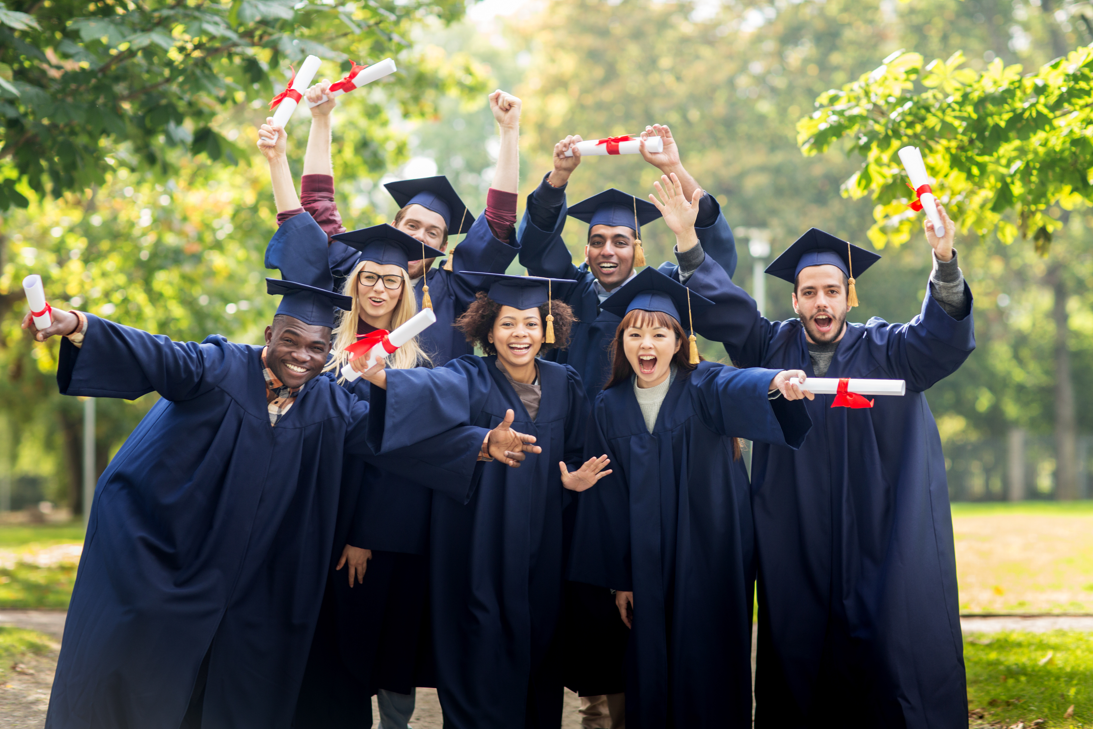 Diverse group of college graduates celebrating with diplomas